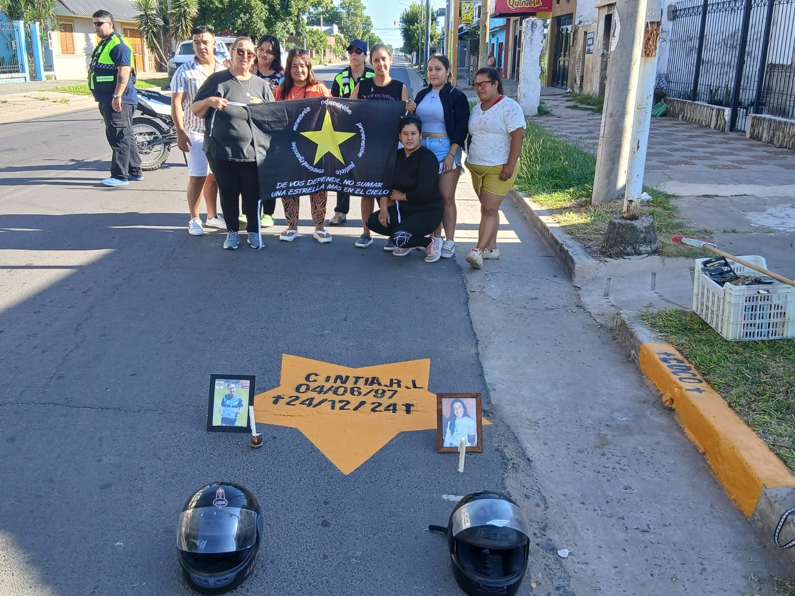 Familiares y vecinos junto a la estrella amarilla de Cintia, con cascos apoyados sobre el asfalto